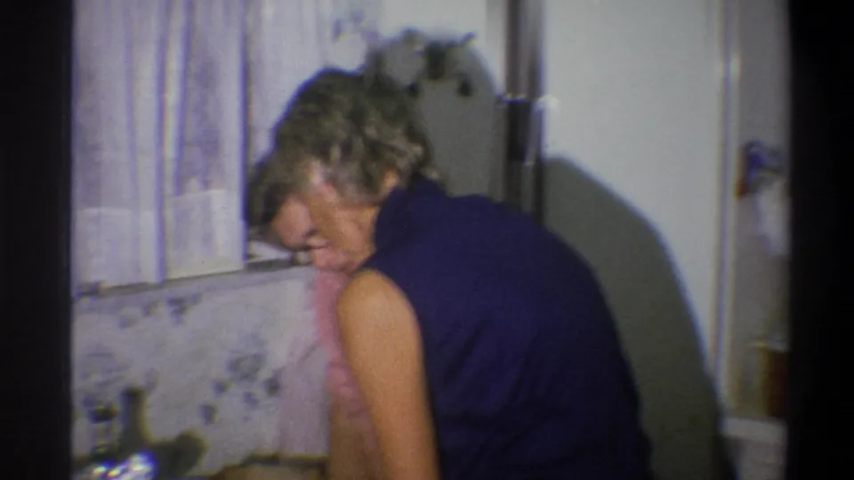 Two mature women lean close together at the kitchen counter in the 1973 Troy home-movie footage.