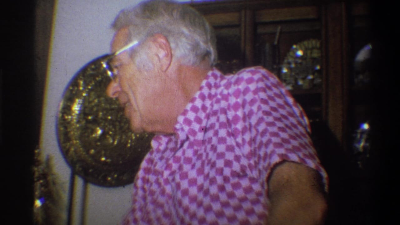 Older man in glasses and a pink checkered shirt seen indoors in Troy, New York, 1973 home-movie footage.