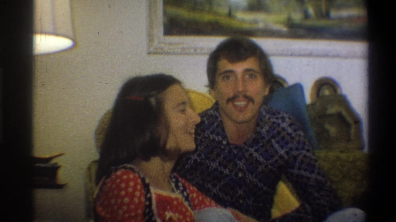 Young couple seated close together on a couch in a living room.