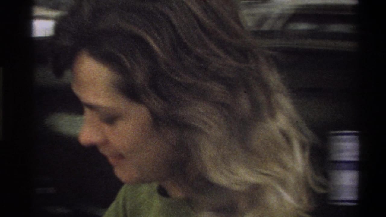 Close view of a young woman in profile, with dark car bodywork behind her.