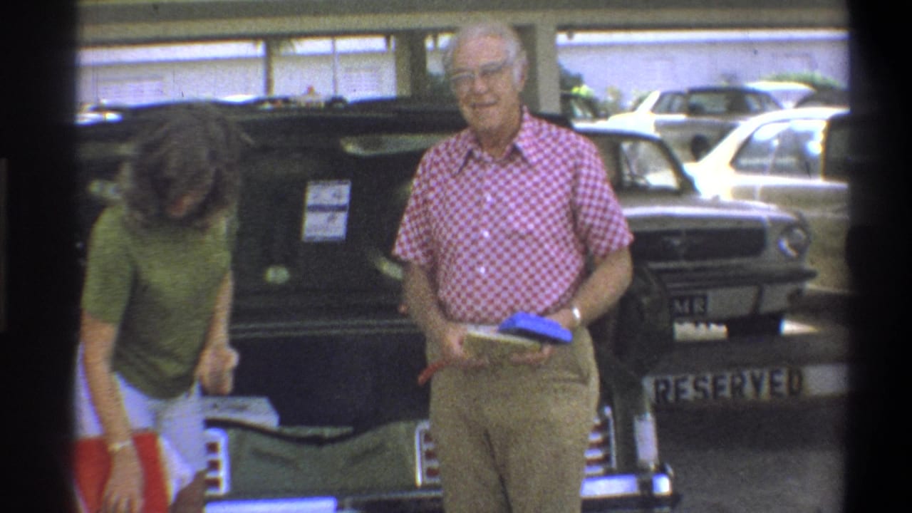 In Troy, New York, 1973, two adults appear to load a classic car in a covered parking area before travel.