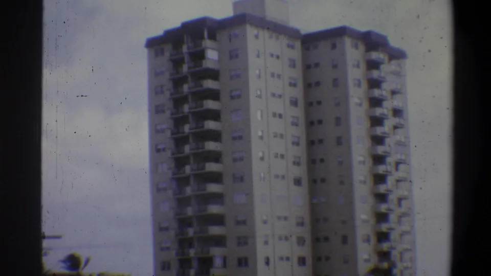 Corner view of high-rise apartment tower, Troy New York area, 1973; aged 8mm stock shows blue-gray color shift, grain, and building's angular facade.