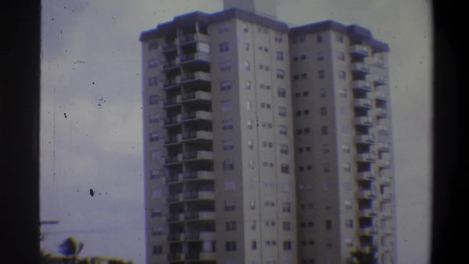 Concrete residential high-rise with horizontal balconies and window grid, circa 1973 Troy, New York area, 8mm with visible dust spots.