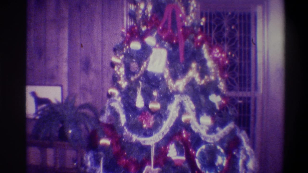 Christmas tree in a private living room, Troy New York, 1973 — red tinsel, silver garland swags, round ball ornaments; 8mm film with purple dye-fade.