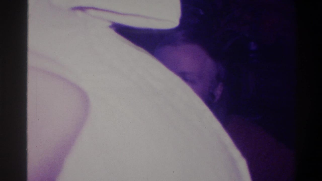 Motion-blurred transitional frame; large overexposed white shape dominates; partial figure visible at lower right.