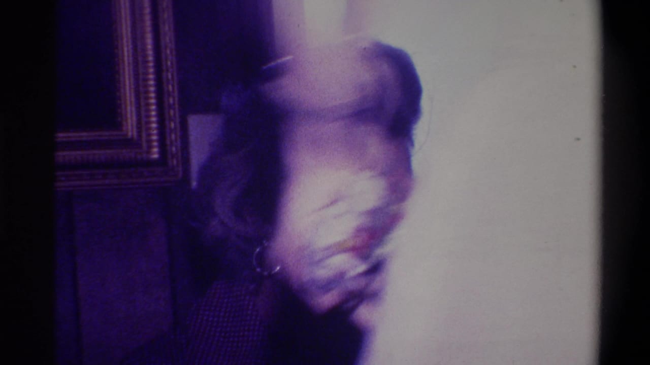 Motion-blurred person moving through a wood-paneled domestic interior, captured on 8mm film circa 1973, Troy, New York.
