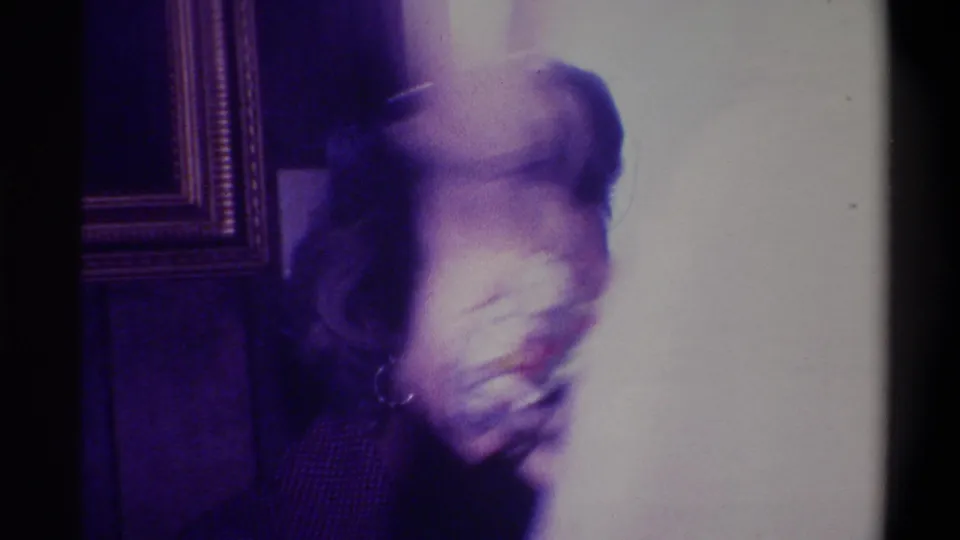 Motion-blurred person moving through a wood-paneled domestic interior, captured on 8mm film circa 1973, Troy, New York.