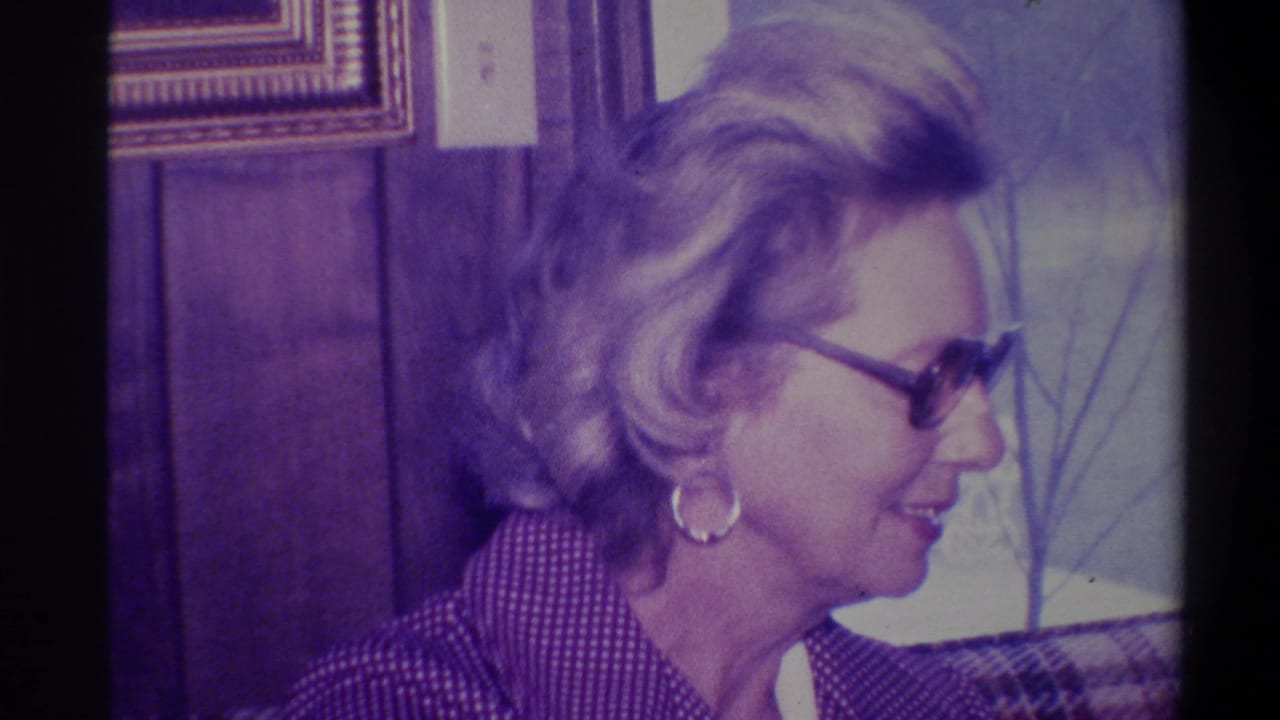 Profile view of a woman with styled blonde bouffant hair, dark-rimmed glasses, and gold hoop earring in a wood-paneled domestic interior, Troy, New York, circa 1973