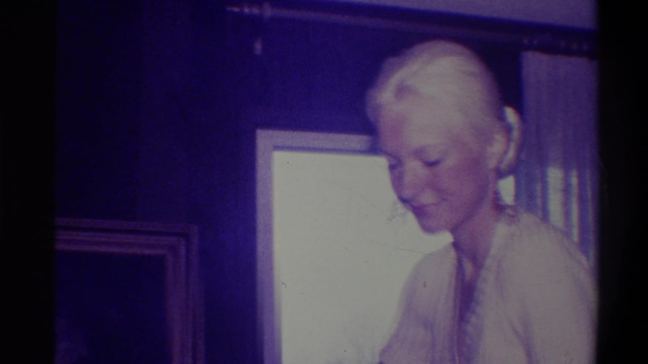 Same woman seen from a different angle looking down; wood-paneled wall and gold-framed picture visible behind her.