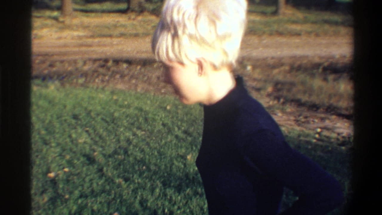Young woman with short blonde hair in left-side profile, dark turtleneck sweater, outdoors in natural light — 8mm home movie footage, Gainesville, Florida, circa 1974.