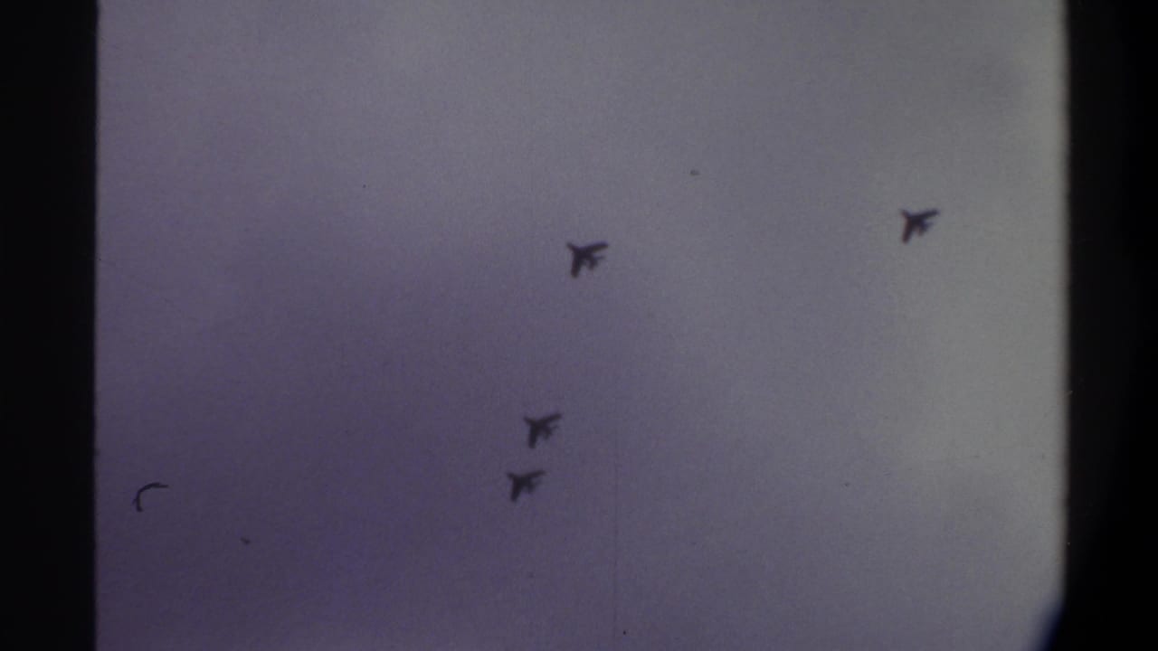 Four swept-wing jet silhouettes crossing an overcast sky on aged 8mm film, Gainesville, Florida, 1974.