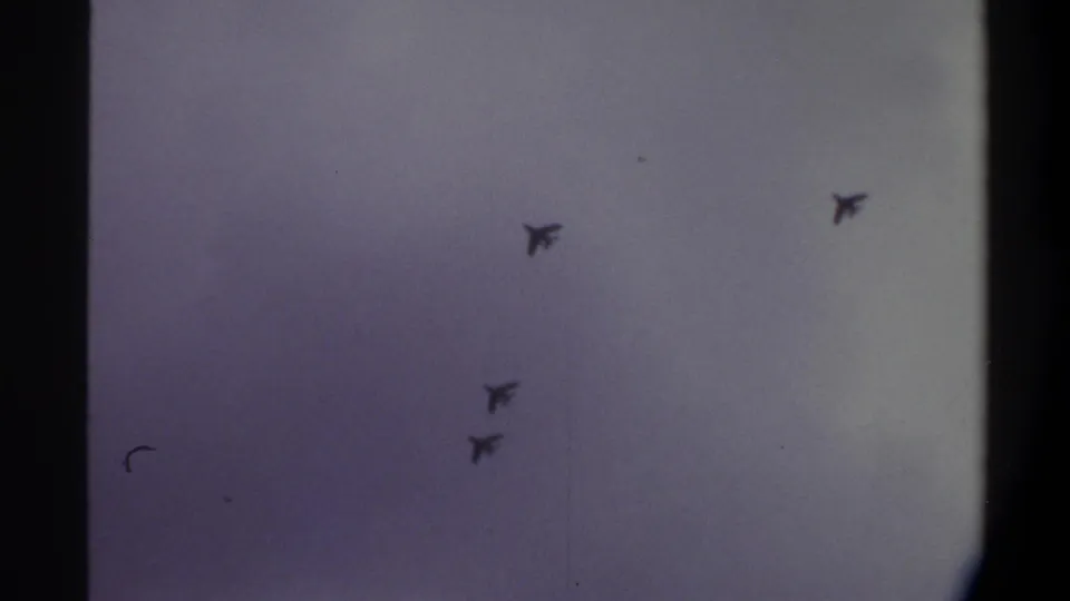 Four swept-wing jet silhouettes crossing an overcast sky on aged 8mm film, Gainesville, Florida, 1974.