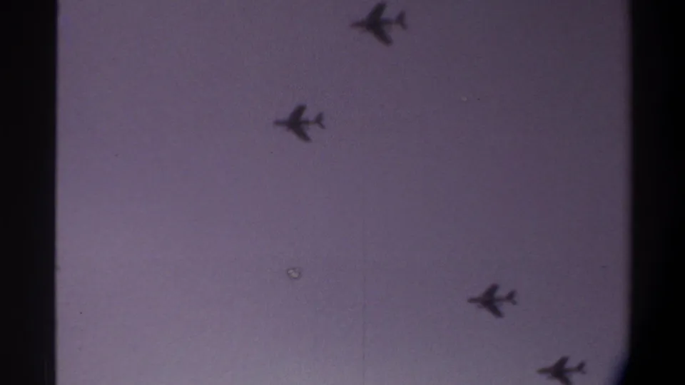 Jets spread across overcast sky at clip end on 8mm film, Gainesville area, 1974; film dust spot artifact visible near center.