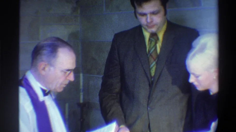 Officiant reads the marriage rite as the groom bows his head; 8mm film consistent with mid-1970s wedding documentation, Gainesville, Florida area.