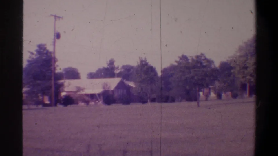 Later pan position showing a low-roofline residential building and utility pole across a wide suburban lawn in Gainesville, Florida, circa 1974.