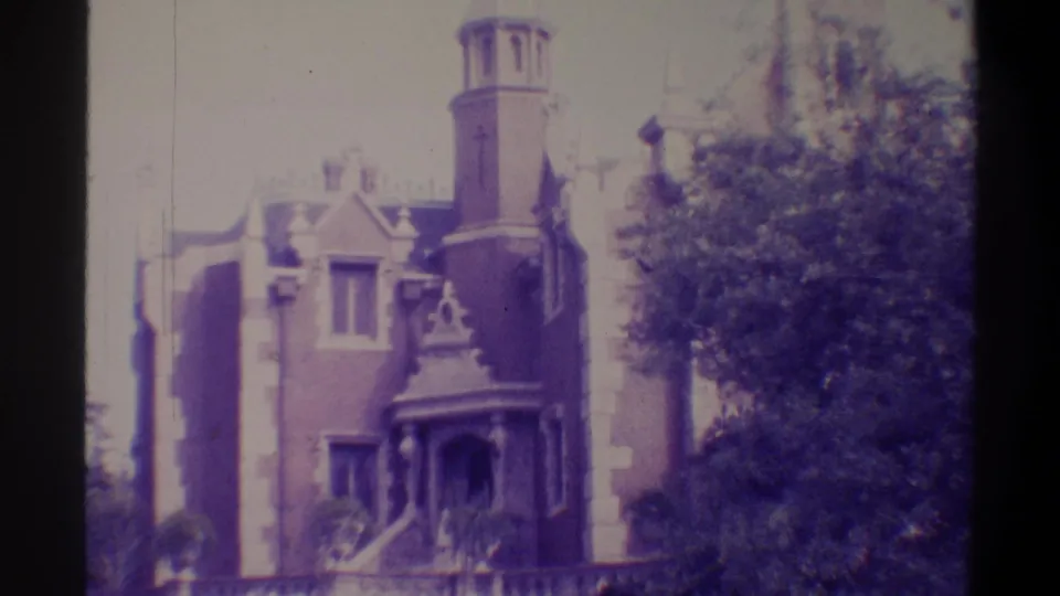 Gothic Revival building, Gainesville, Florida, 1974 — summer trees partially obscure facade; handheld drift visible; purple-toned 8mm.