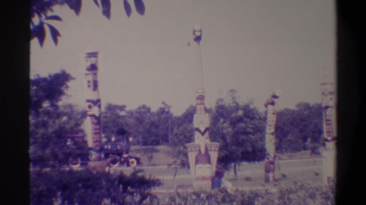 Painted totem-style columns in a park with a small train appearing in the distance, Florida, 1974, 8mm home movie