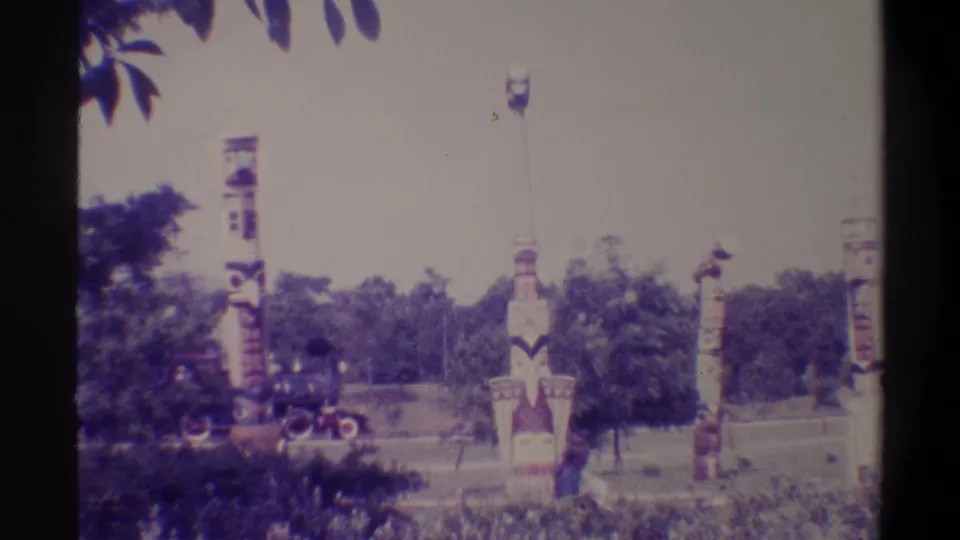 Painted totem-style columns in a park with a small train appearing in the distance, Florida, 1974, 8mm home movie