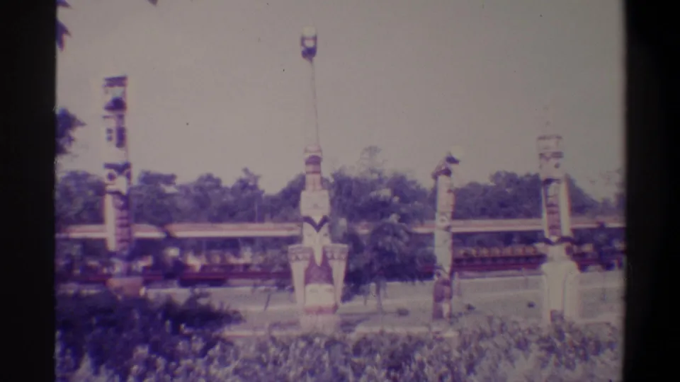 Final 8mm frame showing decorative totem-style structures and a ride train at what appears to be a mid-1970s Florida family attraction.