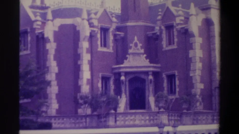 8mm film still from 1974 Florida showing Gothic Revival building facade with ornate decorative window pediment, stone trim columns, and pointed turret; characteristic emulsion color shift.