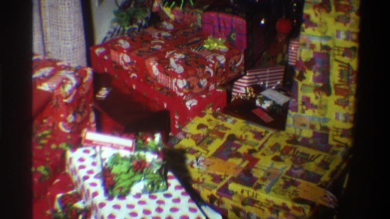 8mm home movie frame circa 1975 showing stacked Christmas gifts in red Santa-print and polka-dot wrapping paper, Gainesville, Florida.