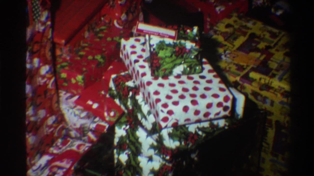 Tighter 8mm frame circa 1975 showing red Christmas-print and white polka-dot wrapped gifts with characteristic mid-1970s film texture.