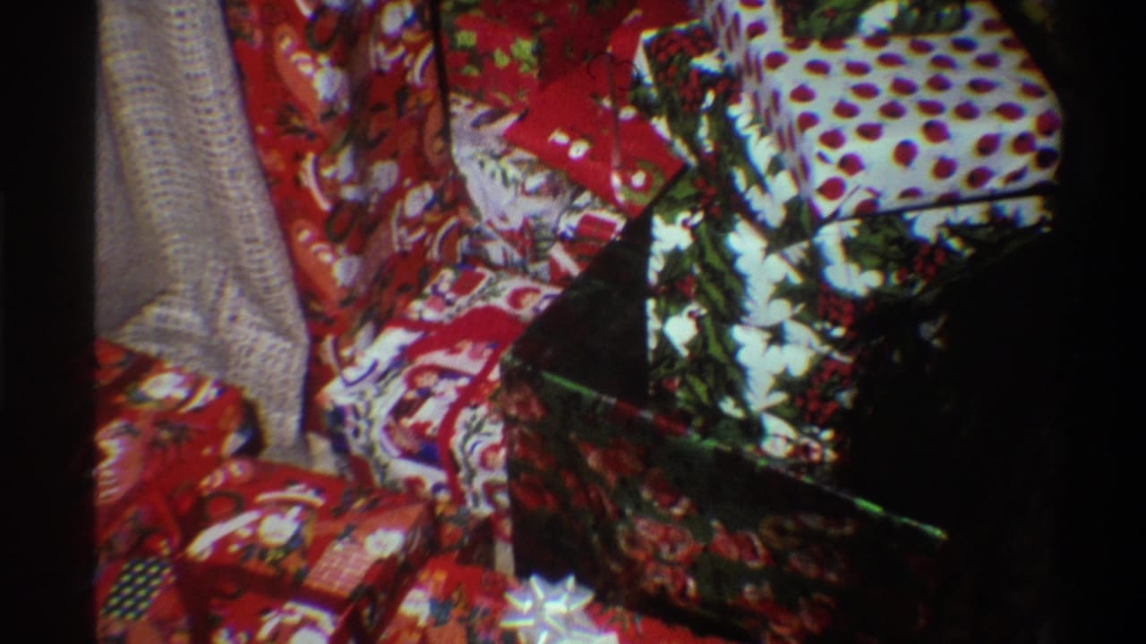 Final 8mm frame circa 1975 showing Christmas gifts and partial Christmas tree branches; film grain and vignetting consistent with 1970s home-movie footage.