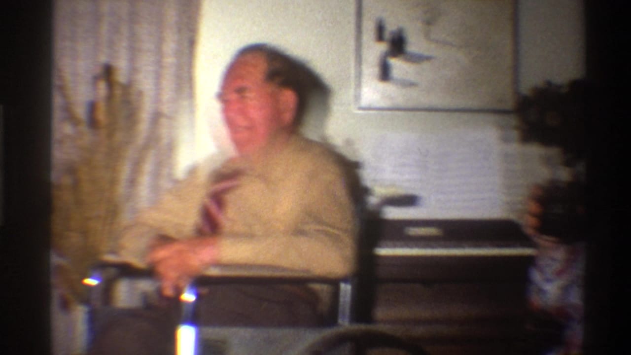 Elderly man in beige shirt and tie seated near a home organ with sheet music; home interior, Gainesville Florida circa 1975, 8mm footage.