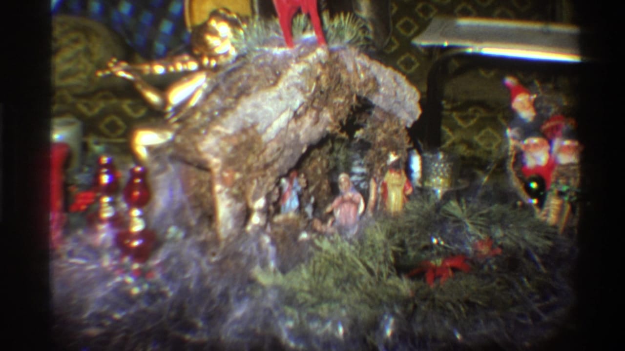Close-up of a bark-covered nativity crèche with small figurines, pine greenery, and mixed Christmas ornaments in a mid-1970s Florida living room.