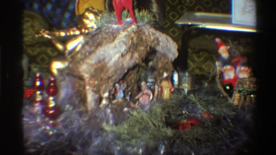 Nativity crèche with bark-covered manger, evergreen base, and mixed holiday ornaments in a private Florida home, circa 1975.