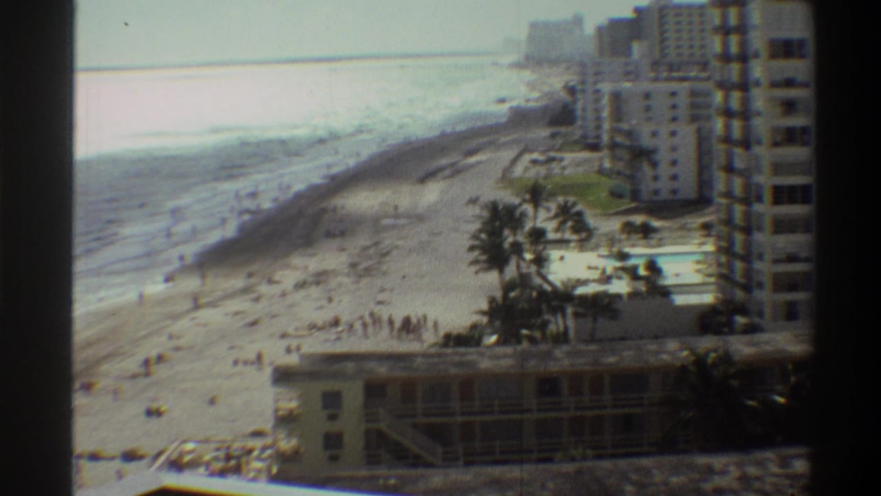 8mm footage of a Florida beach resort, circa 1975, showing palm trees, a hotel pool courtyard, and high-rise towers along the sandy coastline.