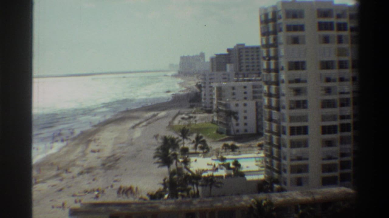 8mm footage circa 1975 of a Florida beachfront resort from a high vantage point, featuring apartment towers, a pool complex, and beach.