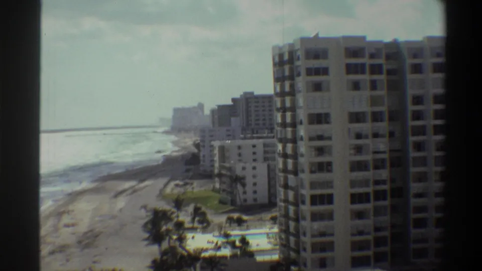 Final 8mm frame circa 1975 showing Florida coastal resort towers, palm trees, and surf from an elevated vantage point.