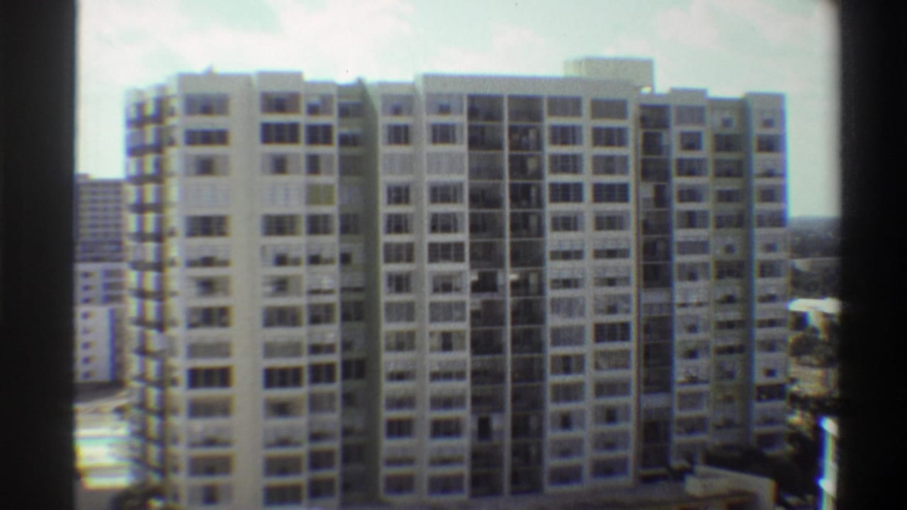 8mm home movie frame, circa 1975, showing a tall mid-century modernist apartment building in Gainesville, Florida, shot from a neighbouring elevated vantage point.