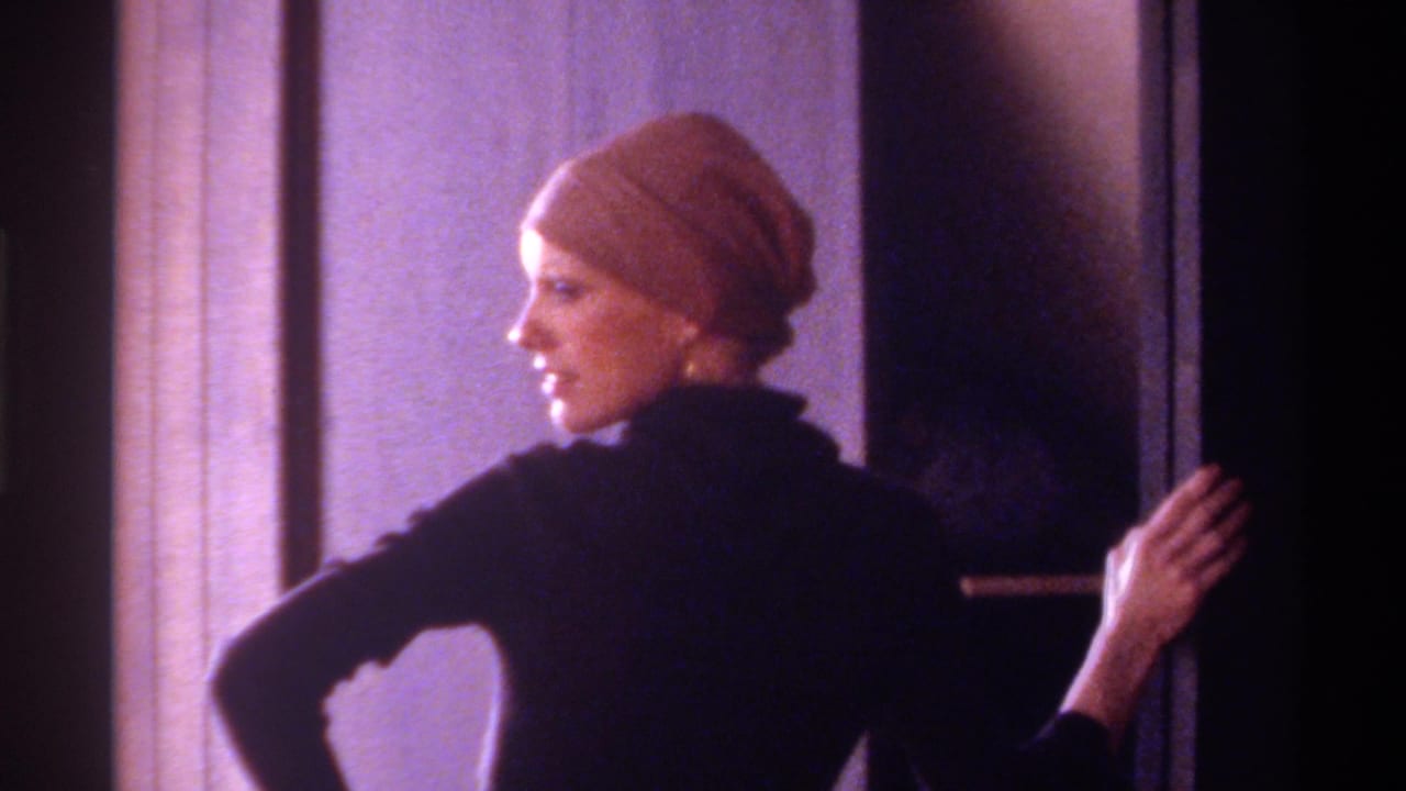 Woman in brown head wrap and black turtleneck posing in back-turned profile inside a private home interior, circa 1975, Florida.