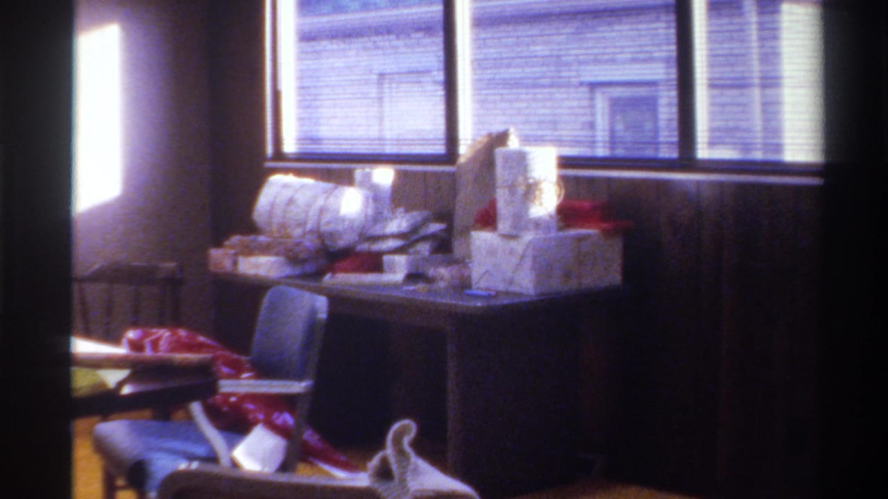 A table piled with Christmas gifts and wrapping supplies in a wood-paneled home interior, Gainesville, Florida, circa 1975.