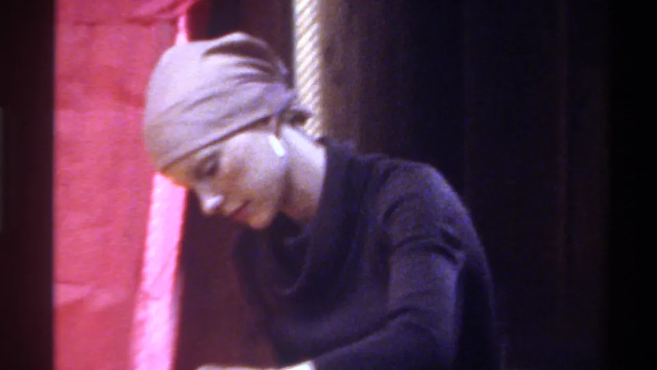 Closer framing reveals the woman's face as she concentrates on her task; pink fabric and a vertical structural element appear behind her; circa 1975, Gainesville, Florida.