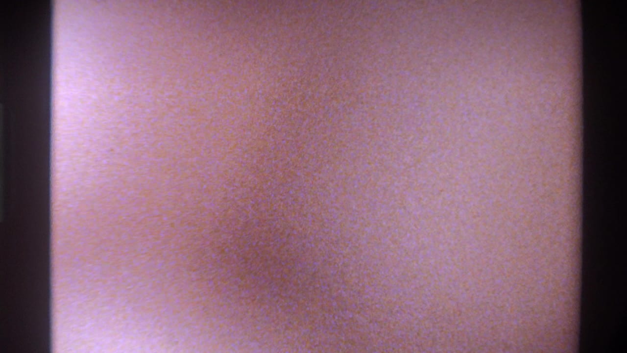 Opening frame of 1975 8mm home movie; camera flare or overexposure produces a warm orange wash with no subjects visible.
