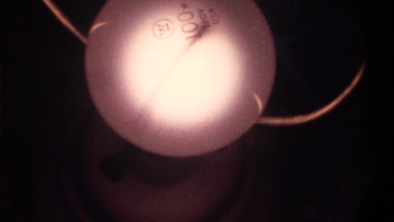Close-up of oversized globe Christmas string lights, overexposed at center; 8mm home movie, Gainesville Florida, circa 1975.