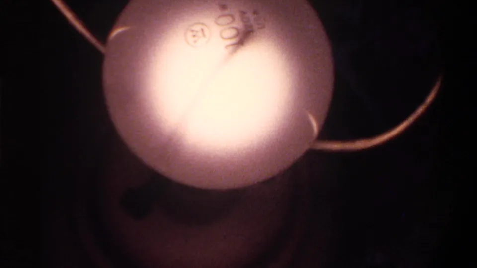 Close-up of oversized globe Christmas string lights, overexposed at center; 8mm home movie, Gainesville Florida, circa 1975.