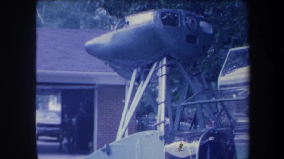 Aircraft cockpit nose on metal stand, rightward camera angle, Yucaipa California ca. 1959, blue-purple aged 8mm film.