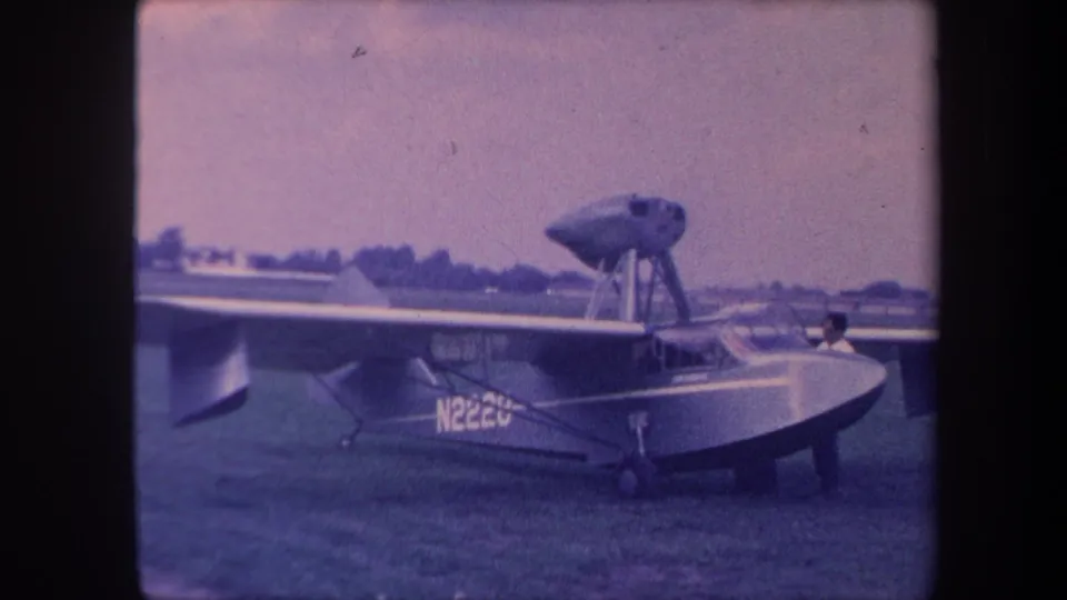 Amphibious flying boat, registration N222U, on a grass airfield in California circa 1959; a figure is visible near the cockpit, captured on 8mm color film.