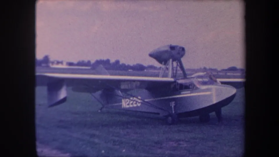 8mm home movie, c.1959, wider view of amphibious aircraft (reg. N222U) on grass airfield showing full wing span and boat hull, likely Yucaipa, California.