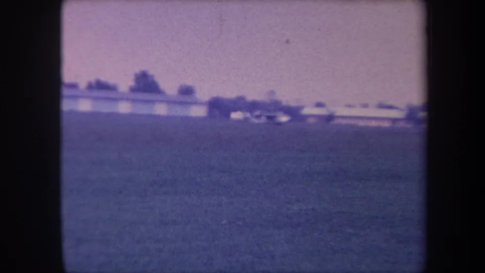 Wider view of the same 1959 Yucaipa rural scene — low buildings and a tree-lined horizon across an open field, with intensified purple-blue emulsion shift.