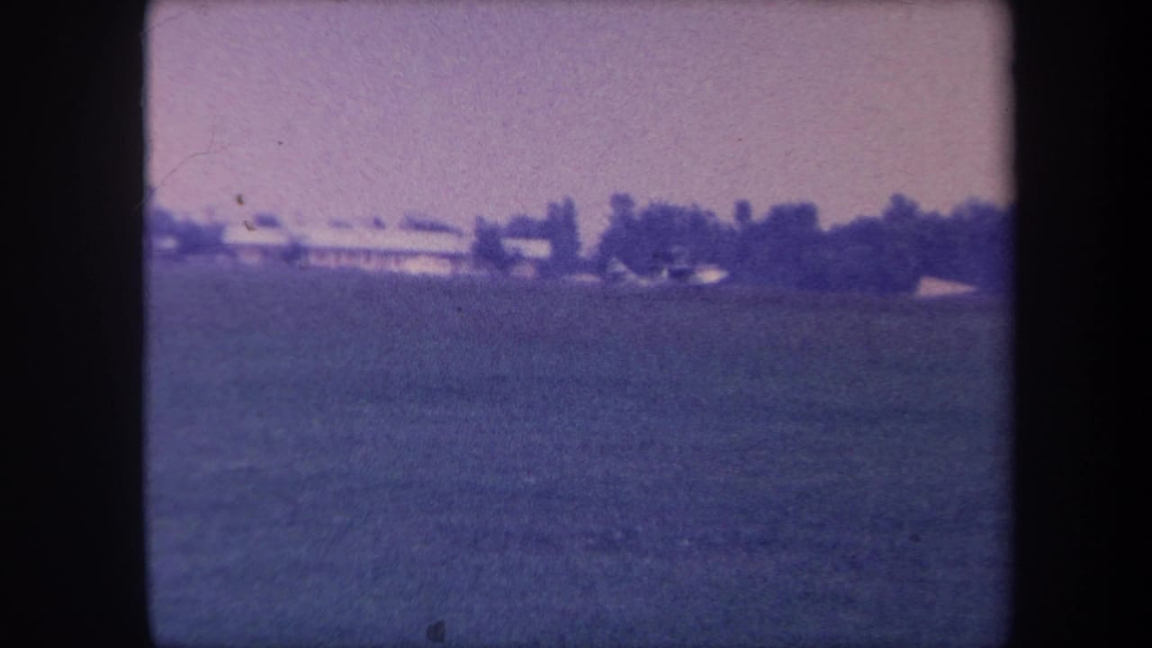 Wide establishing shot of a grass airfield, possibly near Yucaipa, California, circa 1959; no aircraft yet visible; strong purple color cast from aged 8mm film.
