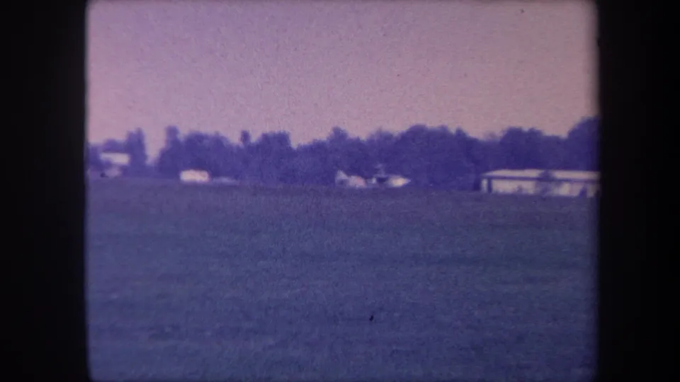 Ground-level view of what may be a small airfield near Yucaipa, California, circa 1959; buildings and treeline visible at right as camera pans.