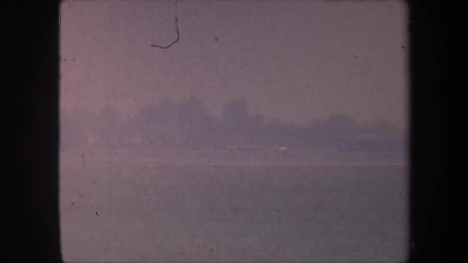 Terminal 8mm frame from circa 1959 sequence, nearly fully overexposed with a faint horizon trace and a visible film-scratch artifact.