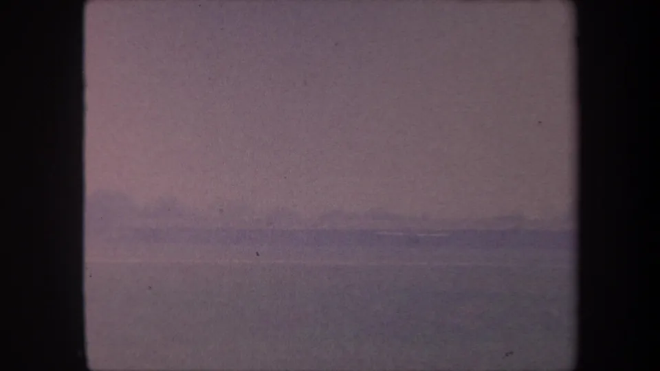 8mm home movie frame circa 1959, California: washed-out purple-pink sky over flat landscape, very low contrast with no identifiable subjects.