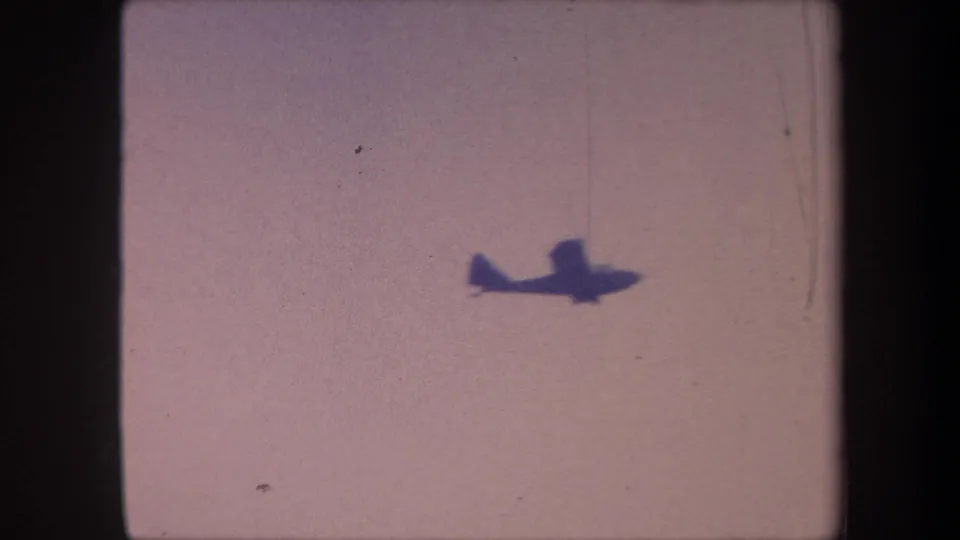 Single-engine propeller aircraft silhouetted against pale pinkish-lavender sky, filmed on 8mm in Yucaipa, California, noted as 1959.
