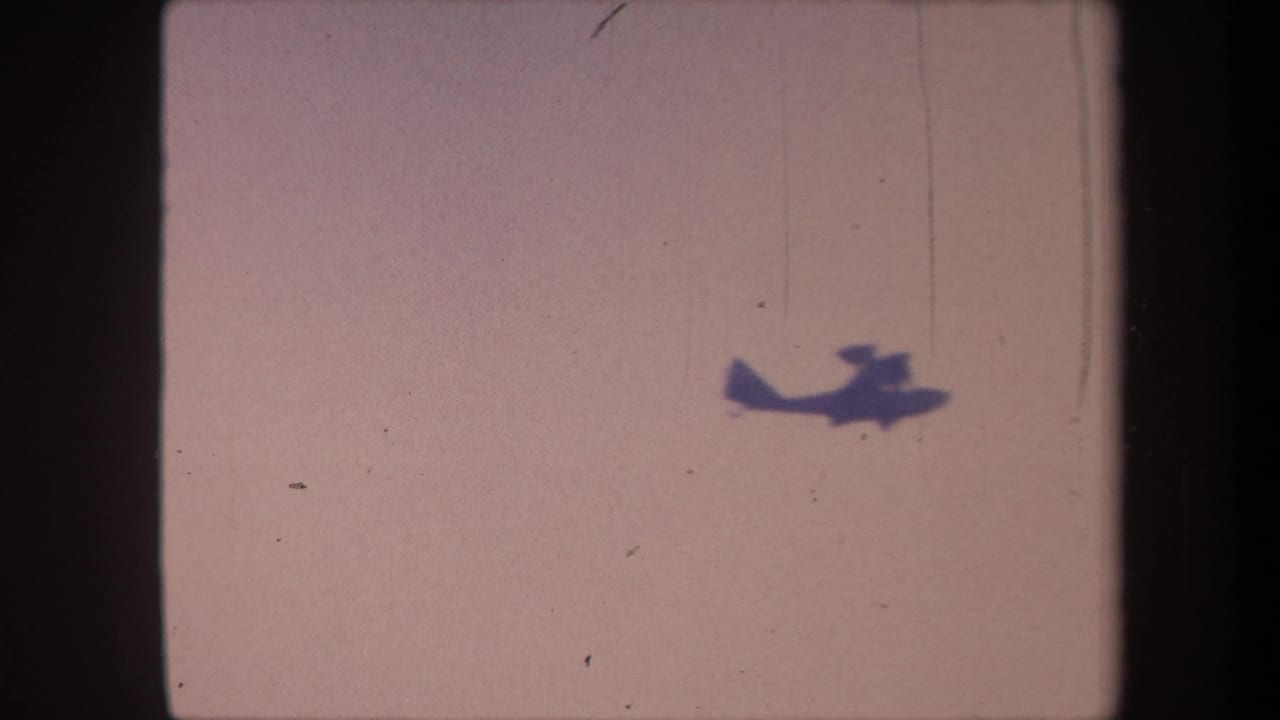 Propeller aircraft moved to upper-right of frame against pale pinkish-lavender sky; 8mm home-movie, Yucaipa, California, 1959.